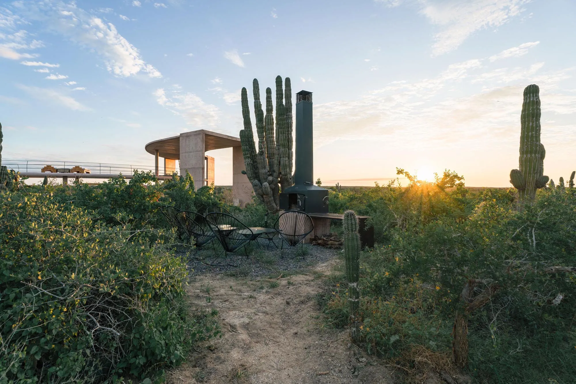 Sunset over the desert scrub, with the villa's concrete pavilion and outdoor fireplace among cardones